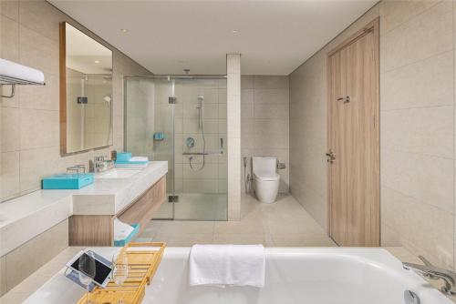 bagno con vasca, doccia e servizi igienici di Waterfront A La Carte Residence a Ha Long