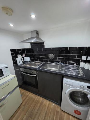 a kitchen with a sink and a washing machine at Cozy Studio Flat, 7mins from CENTRE, Parking, WiFi & Netflix in Killingbeck
