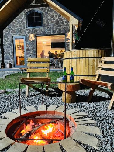 a fire pit in a yard with two picnic tables at Woodlandia Resort Borjomi in Borjomi