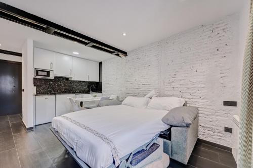 a bedroom with a large bed and a brick wall at Apartamentos Vinomium by Clabao in Logroño