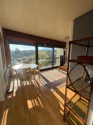 une pièce avec une table et des chaises et une grande fenêtre dans l'établissement Le Nemours, à Thonon-les-Bains