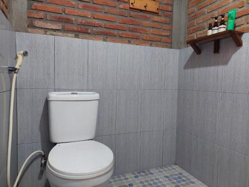 a bathroom with a white toilet and a brick wall at Banyu Kasongan Homestay in Bantul