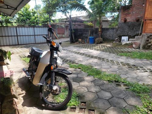 a motorcycle parked on a stone walkway in a yard at Banyu Kasongan Homestay in Bantul