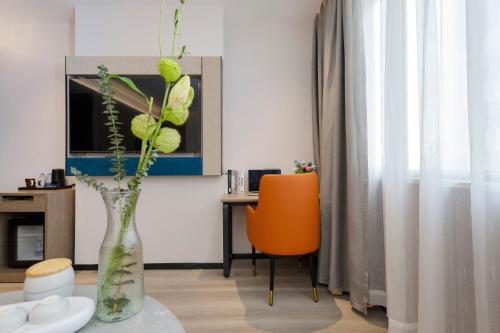 a vase with flowers on a table in a room at 逸方里广州北京路海珠广场地铁站店 in Guangzhou