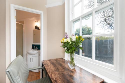 a vase of flowers on a wooden table with a window at The Vicarage Tooting, SW17 in London