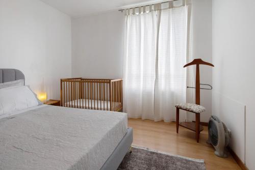 a bedroom with a bed and a chair and a window at São Roque Apartment in São Roque