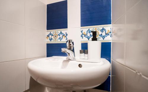 La salle de bains est pourvue d'un lavabo blanc et de carrelage bleu et blanc. dans l'établissement Pitti13, à Florence
