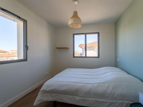 a bedroom with a bed and two windows at Maison neuve proche océan, terrasse, parking, 8 pers - FR-1-319-585 in Biscarrosse