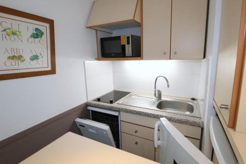 une petite cuisine avec un évier et un micro-ondes dans l'établissement La Baie - Hoedic By Tranquil at Home, à La Baule