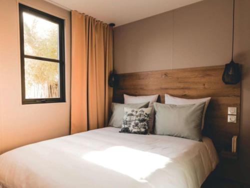 une chambre avec un lit blanc avec une fenêtre dans l'établissement Camping Les Franquettes - Aquatique Vacances, à Grayan-et-lʼHôpital