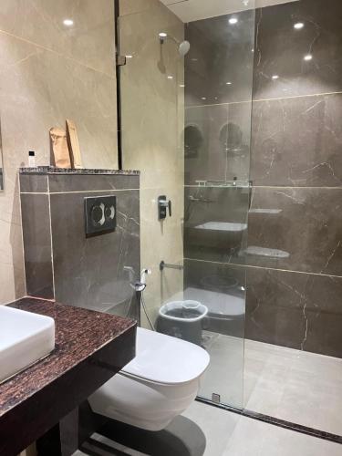 a bathroom with a toilet and a glass shower at The Harilal in Patna