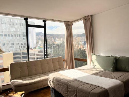 a bedroom with a couch and a large window at Soleado departamento con vistas hermosas Sopocachi in La Paz