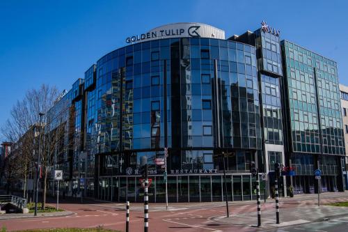 a glass building with a sign on top of it at Golden Tulip Leiden Centre in Leiden