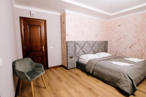 a bedroom with a bed and a chair in it at Soprano Inn Hotel in Pasiky-Zubryts'ki