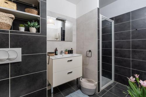 La salle de bains est pourvue d'une douche et d'un lavabo blanc. dans l'établissement Annecy, calme, terrasse, parking box, à Annecy