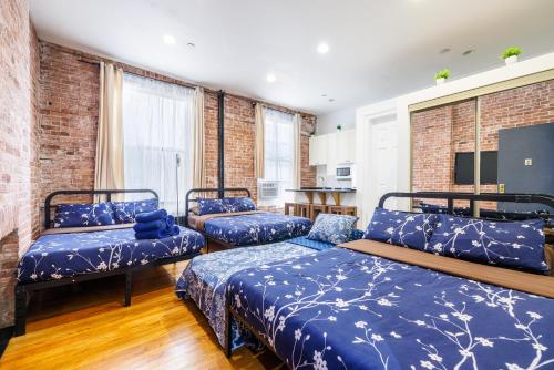a room with three beds with blue sheets at Studios in New York in New York