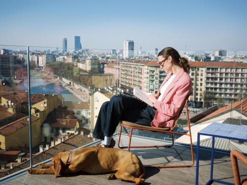 a woman sitting in a chair with a book and a dog at 21 House of Stories Navigli in Milan