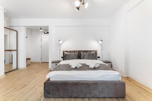 a bedroom with a large bed with white walls and wooden floors at Sea Reflections in Infinity Pool & Spa Resort in Mamaia Sat/Năvodari