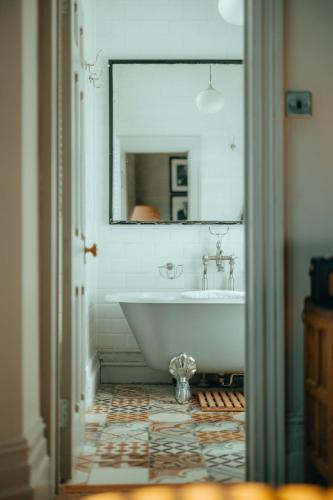 a bathroom with a tub and a mirror at The Rudloe Near Bath - Marco Pierre White in Corsham