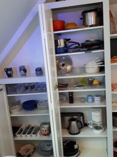 - un garde-manger blanc avec de la vaisselle et des ustensiles dans l'établissement Charmant appartement près de Berstett - 42 m² avec jardin, à Berstett