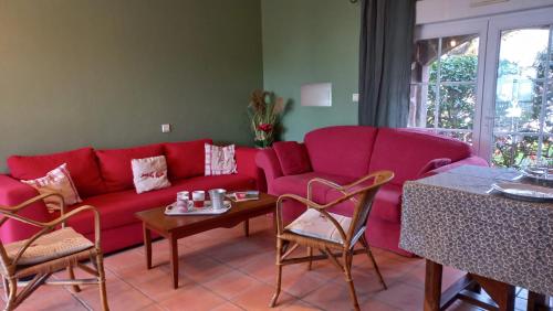 un salon avec un canapé rouge et une table dans l'établissement La Maison des étoiles, à Noailhac