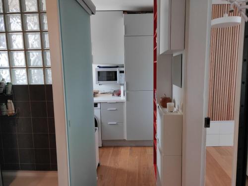 une petite cuisine avec des armoires blanches et un micro-ondes dans l'établissement Père Corentin - CI - Bright apt for 2pers at Porte d'Orléans, 14è, à Paris