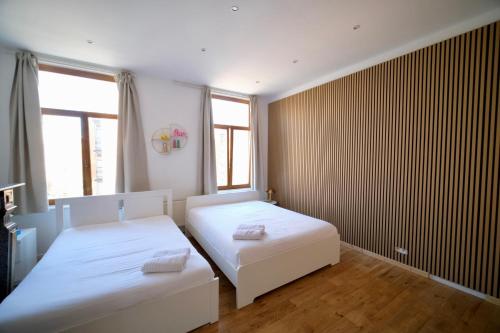 two beds in a room with two windows at Easy Stay - City Center in Brussels