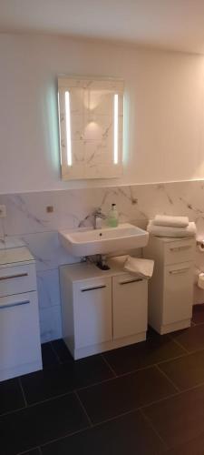 a white bathroom with a sink and a mirror at Schönes Zimmer mit Küche und Bad im Taunus in Waldsolms