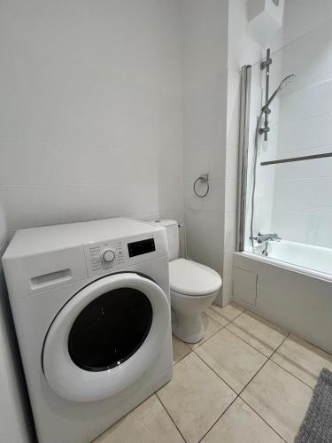 a white bathroom with a toilet and a washing machine at Superbe T2 à 15 min de Lyon in Sainte-Foy-lès-Lyon