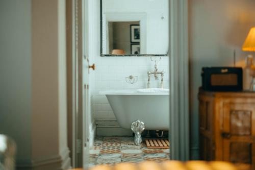 a bathroom with a white tub and a mirror at The Rudloe Near Bath - Marco Pierre White in Corsham