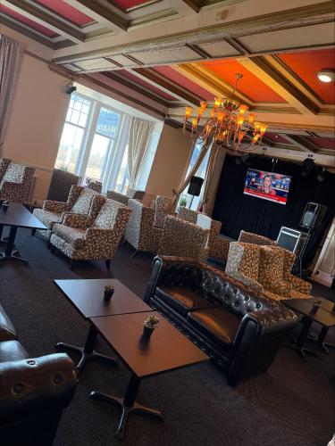 a living room with a couch and chairs and a tv at The Savoy Hotel in Blackpool