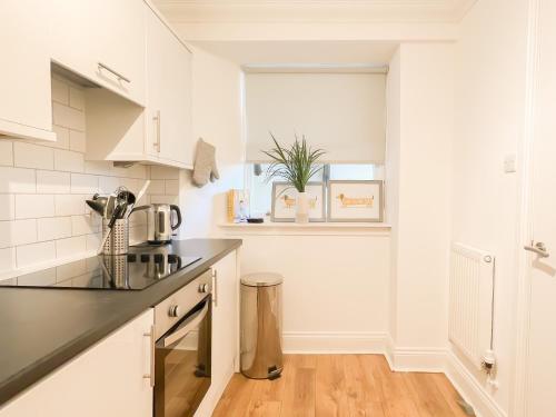 a kitchen with white cabinets and a black counter top at Cozy 1 bed Blythswood Apartment in Glasgow