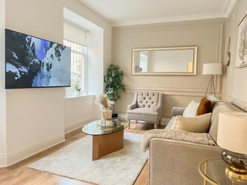 a living room with a couch and a tv on a wall at Cozy 1 bed Blythswood Apartment in Glasgow