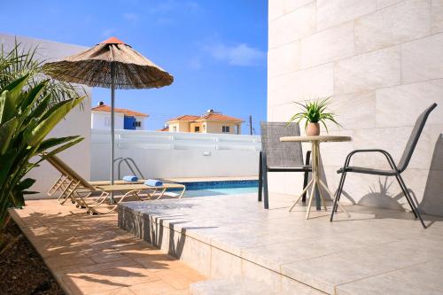 a patio with a table and chairs and an umbrella at Villa Calliopi in Protaras