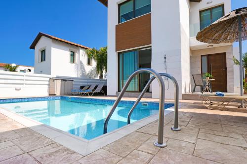 a swimming pool with an umbrella next to a house at Villa Calliopi in Protaras