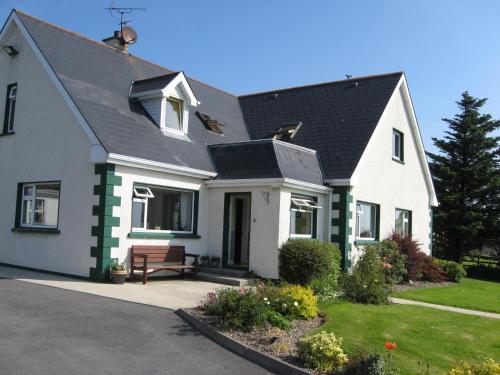 a white house with a bench in the driveway at Seacrest Guesthouse in Mullaghmore