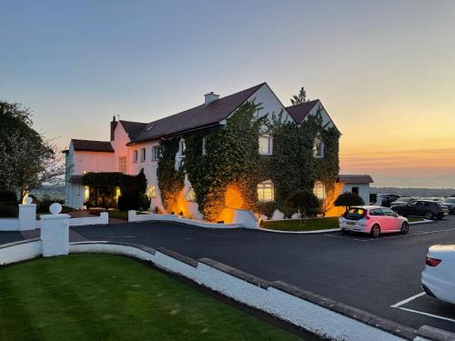 a large house with a car parked in a parking lot at Highgrove House Hotel in Loans
