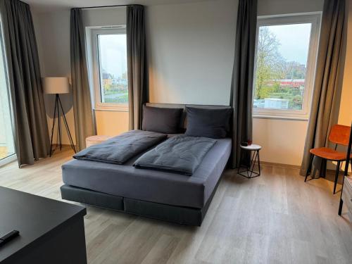 a bed in a room with two windows at Exklusives Wohnen im historischen Wasserturm dem Highlight von Delitzsch WE317 in Delitzsch