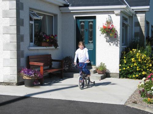 a young child riding a bike in front of a house at Seacrest Guesthouse in Mullaghmore