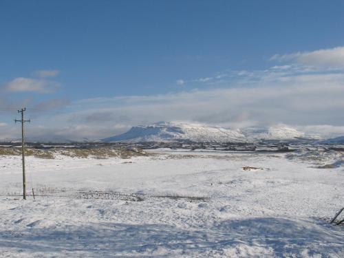 a snow covered field with a mountain in the background at Seacrest Guesthouse in Mullaghmore