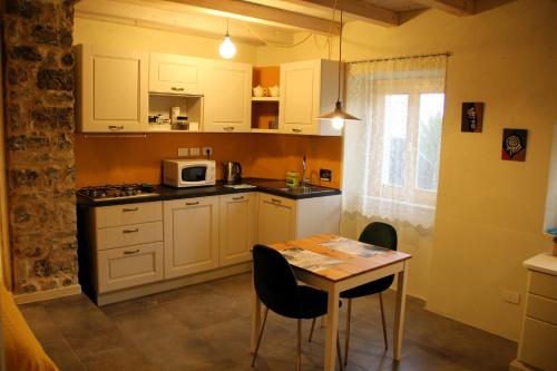 eine Küche mit weißen Schränken und einem Tisch mit Stühlen in der Unterkunft La Casa del Sole a Cosy Nest in Lunigiana, Tuscany in Giucano