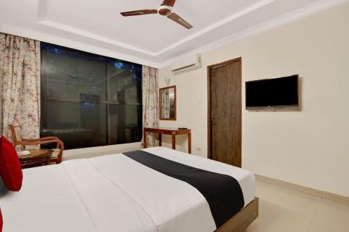 a bedroom with a bed and a flat screen tv at Capital O Elegant Amethyst Business Hotel Near Ragigudda Sri Prasanna Anjaneyaswamy Temple in Bengaluru