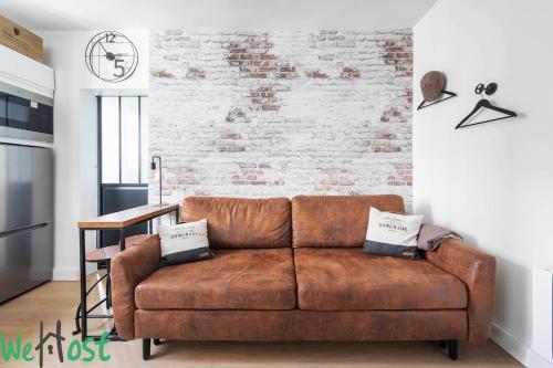 - un canapé brun dans le salon avec un mur en briques dans l'établissement Charenton 2 - CI - Paris apt, 2 ppl - Bercy - Gare de Lyon, à Paris