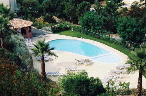 une vue aérienne d'une piscine avec des chaises et des palmiers dans l'établissement Appt 87m2 - 3 étoiles - parking - wifi - clim - piscine, à Roquebrune-sur Argens
