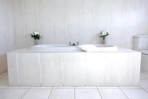 a white bathroom with a tub and a toilet at Highgrove House Hotel in Loans
