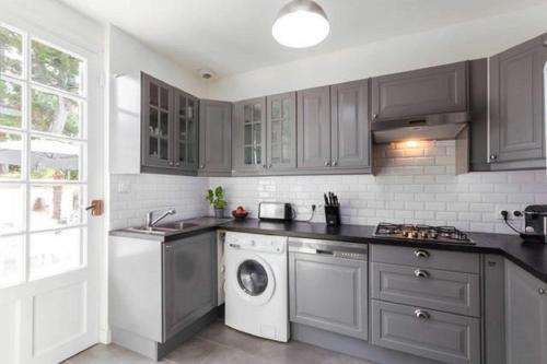 une cuisine avec des placards gris et un lave-linge dans l'établissement Agréable, jardin, toute équipée, proche du marché, plage à 300m, à La Baule