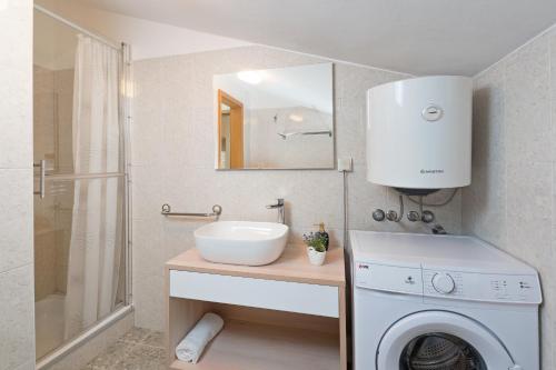 a bathroom with a sink and a washing machine at Apartment Roce in Rabac