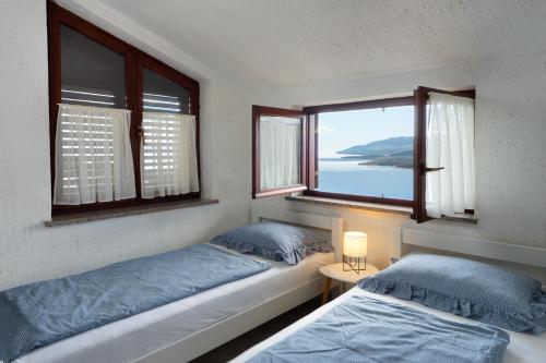 two beds in a room with two windows at Apartment Roce in Rabac