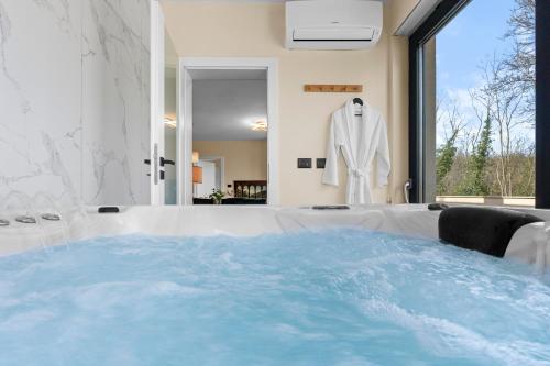 a bathroom with a tub with a white suit in the window at Charming Villa Harmonia with Heated pool and Indoor Jacuzzi surrounded by nature in Pićan