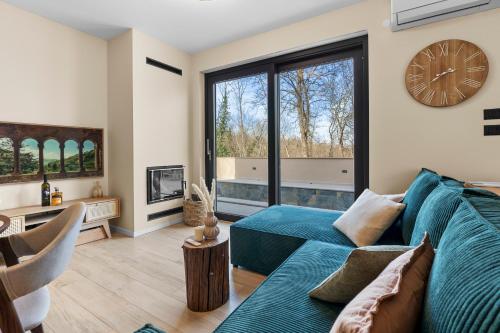 a living room with a blue couch and a large clock at Charming Villa Harmonia with Heated pool and Indoor Jacuzzi surrounded by nature in Pićan